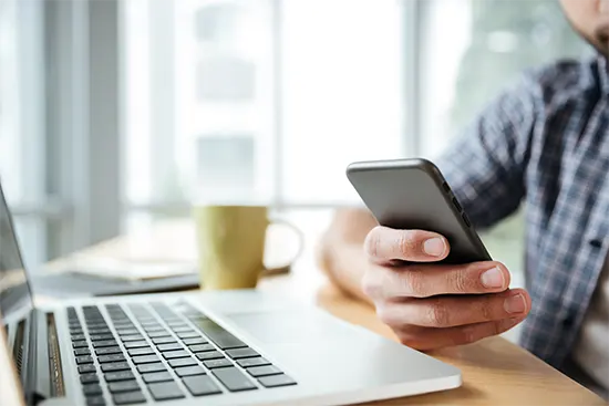 servicii marketing online bărbat care folosește telefon mobil în timp ce lucrează la laptop